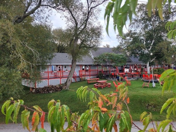 Un edificio de fachada roja, con un porche cubierto y mesas al aire libre.