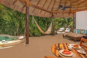 A tropical resort room with a thatched roof, a pool, a hammock, and a dining area with breakfast. - Viceroy Riviera Maya All Inclusive (Playa del Carmen)