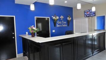 Una recepción con pared azul, puerta negra y pantalla de televisión.