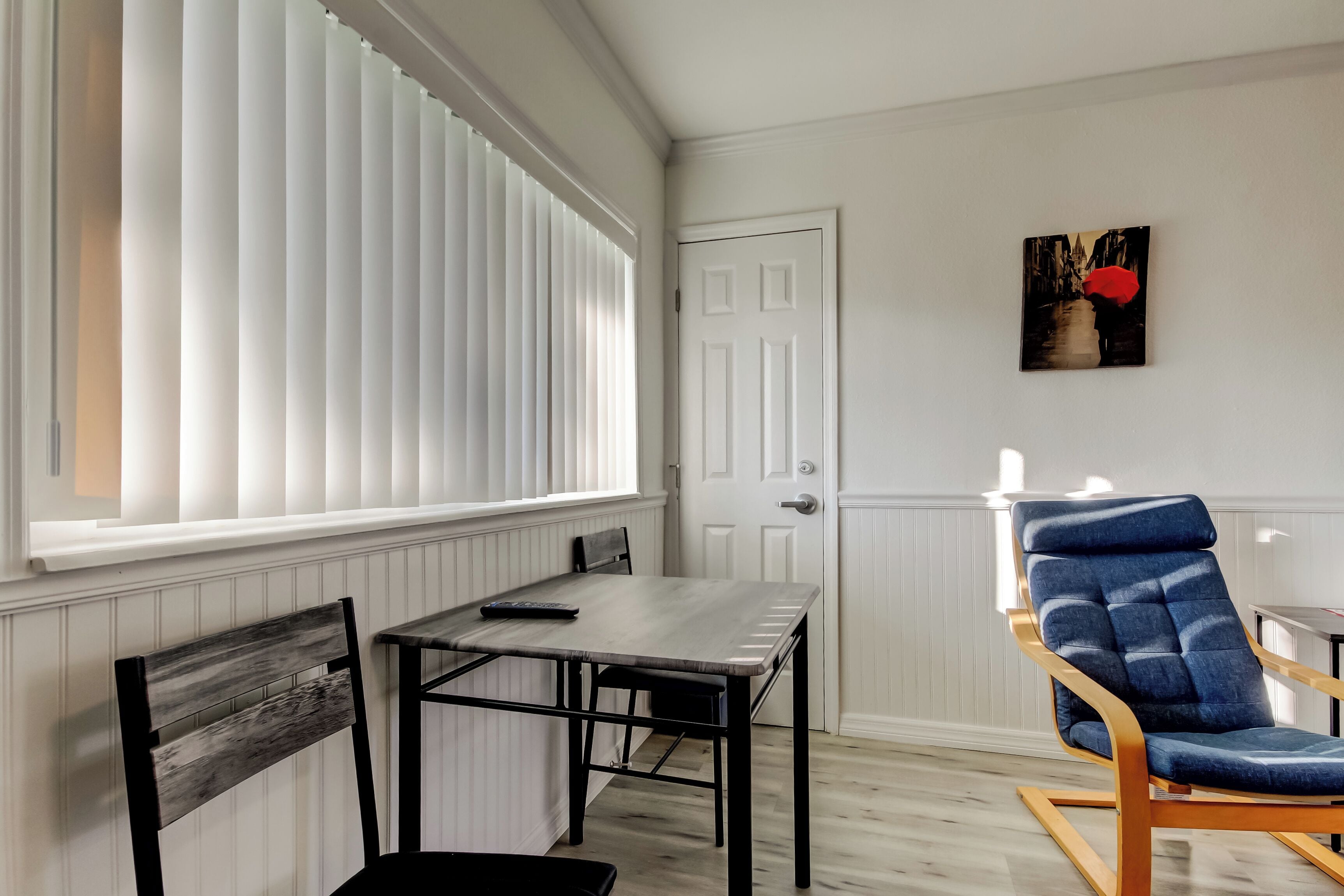A room with a dining table, a chair, a rocking chair, and a door.