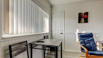 A room with a dining table, a chair, a rocking chair, and a door.