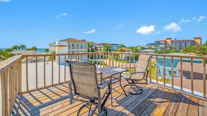 A wooden deck with outdoor furniture overlooking a pool and resort buildings. - Carousel Suites (Redington Shores)