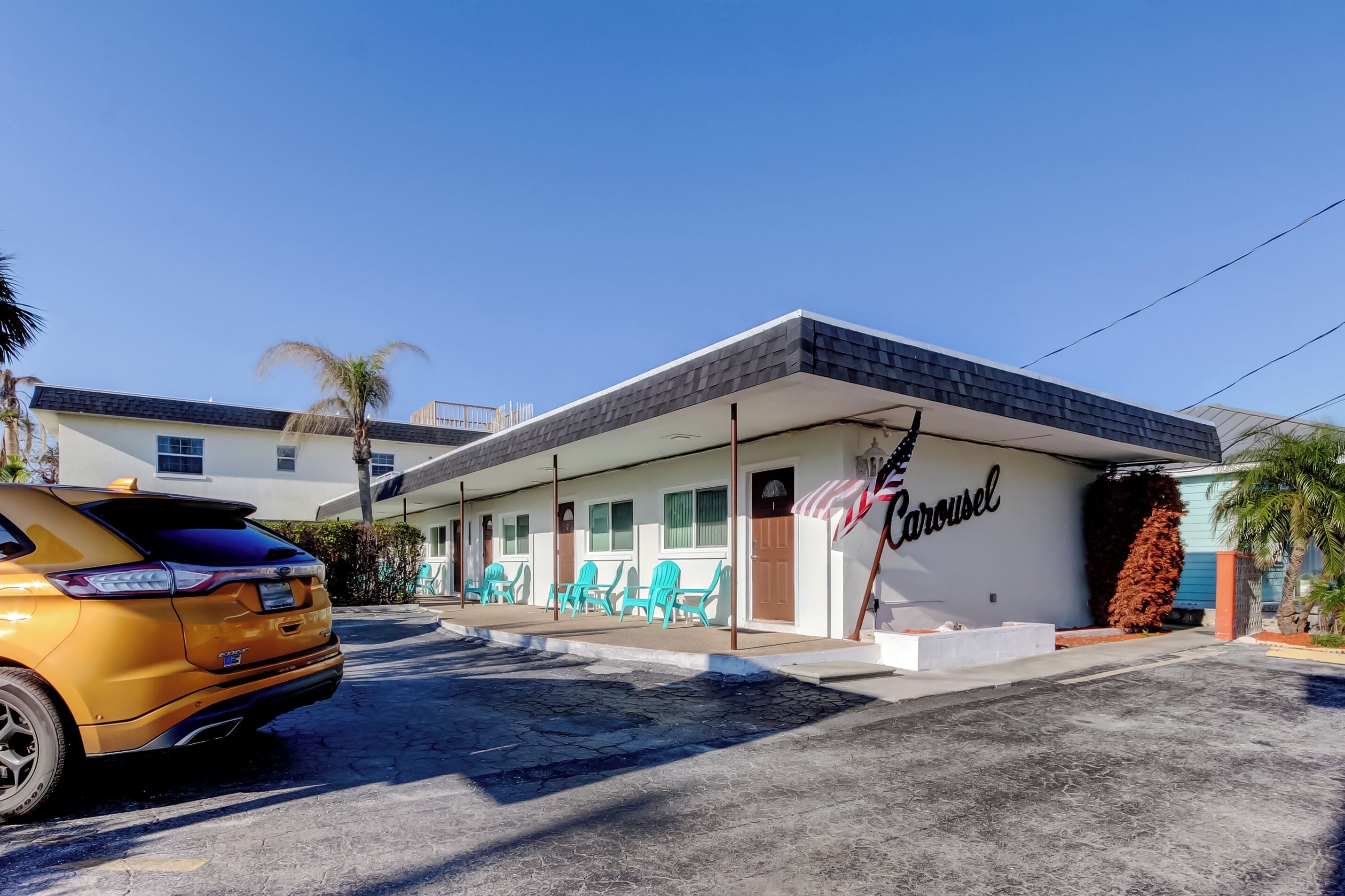 Un motel con un cartello che riporta la scritta 'Carousel' e un'auto parcheggiata davanti.