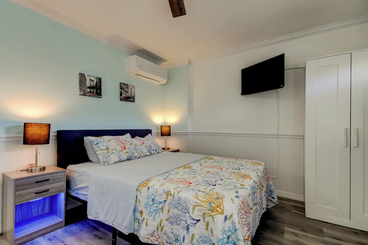 A bedroom with a bed, bedside lamps, a TV, and a wardrobe.