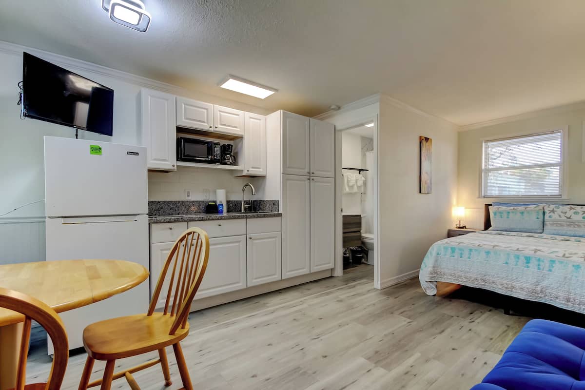 A compact living space with a kitchenette, a dining area, and a bedroom.