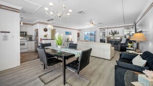 A modern open-plan living space with a dining area, kitchen, and seating area. - Carousel Suites (Redington Shores)