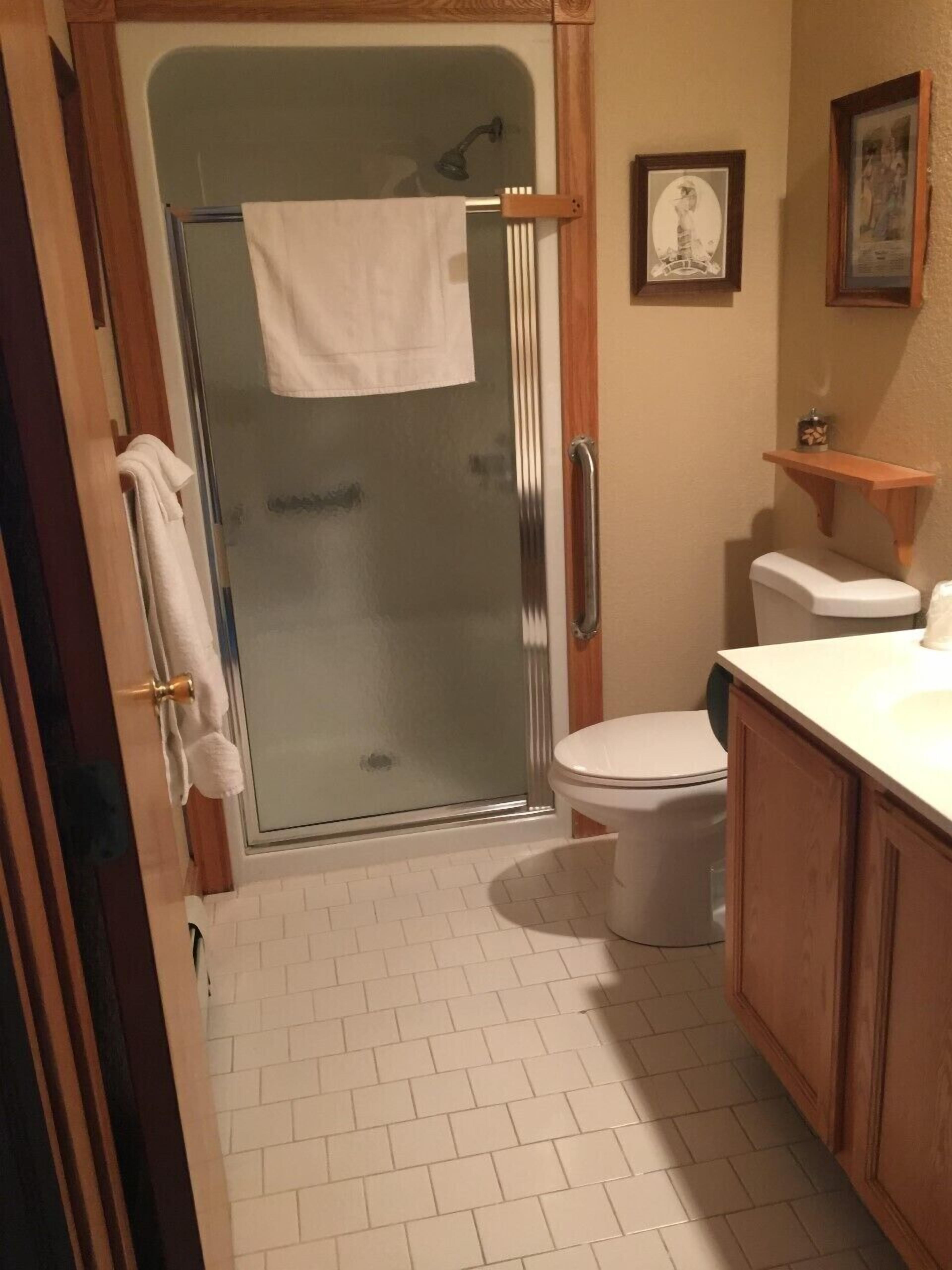 Un baño con mampara de vidrio, inodoro y lavamanos.