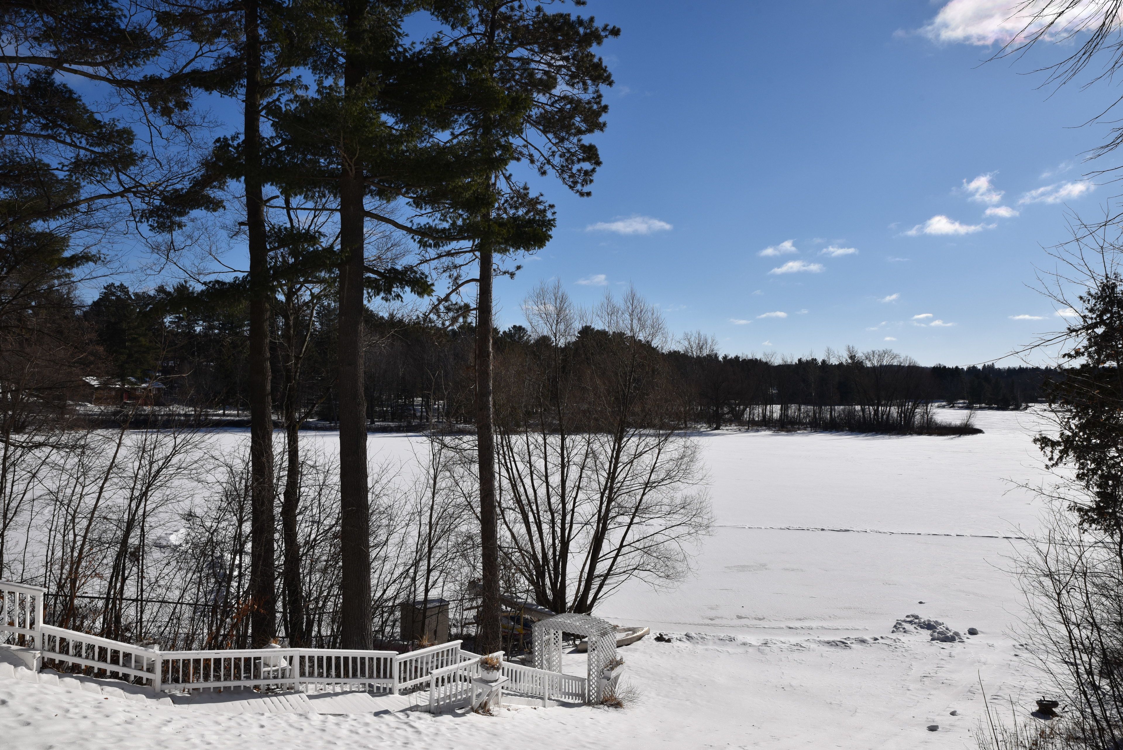 A snow-covered landscape with a wooden deck and a gazebo.