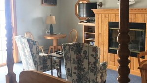 Una cama con dosel, chimenea, televisor y zona de comedor con sillas y mesa.