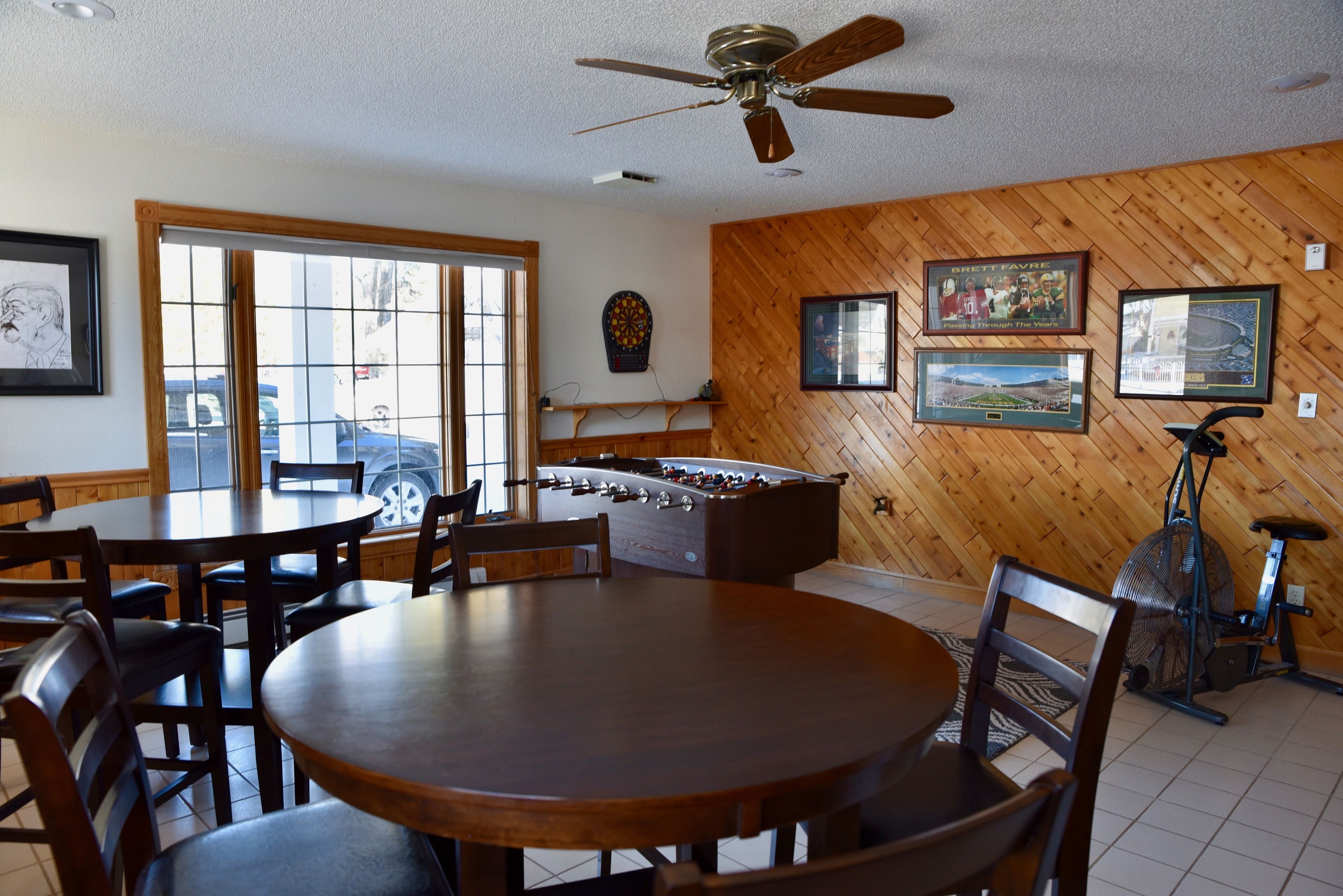 A room with a wooden wall, a foosball table, a ceiling fan, and a bicycle.