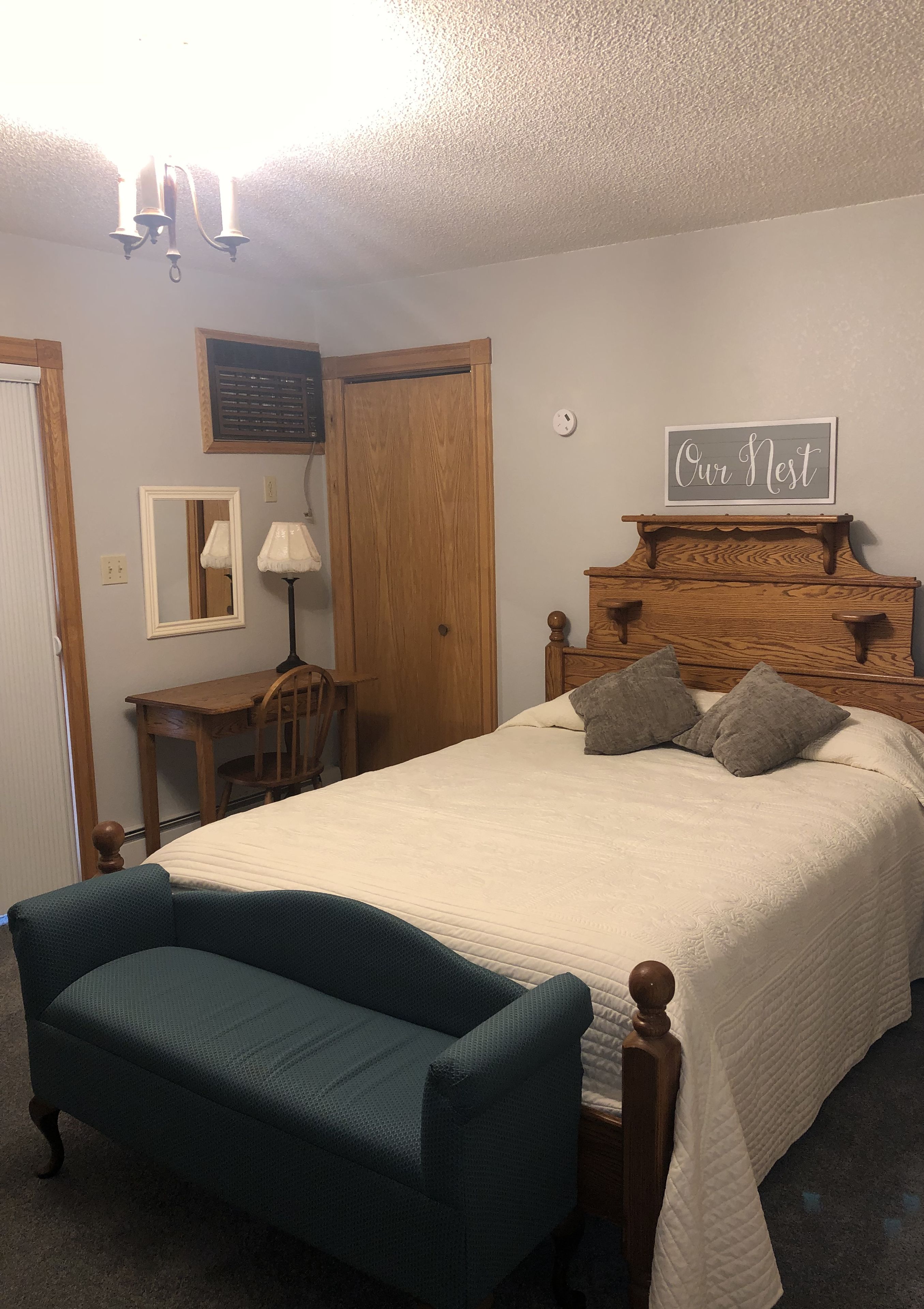 A bedroom with a bed, a desk, a chair, and a bench.