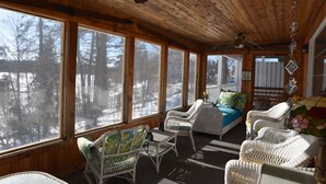 Una cabaña acogedora con ventanas amplias, muebles de mimbre y techo de madera.