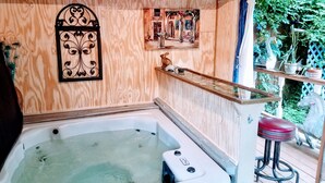 A wooden spa area with a hot tub, decorative wall art, and a small seating area. - 1812 Overture B&B (Kansas City)