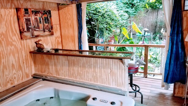 A wooden spa area with a hot tub, wooden beams, and a view of a garden. - 1812 Overture B&B (Kansas City)