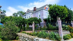 A large, two-story house with a brick facade, surrounded by lush greenery and a black metal fence. - 1812 Overture B&B (Kansas City)