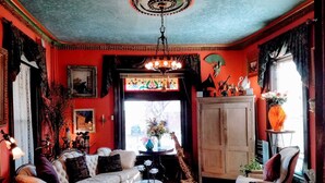 A cozy living room with a sofa, armchairs, a coffee table, and a chandelier. - 1812 Overture B&B (Kansas City)