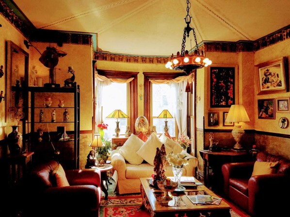 Una habitación tradicional con sofá, sillones, una mesita de centro y un candelabro.