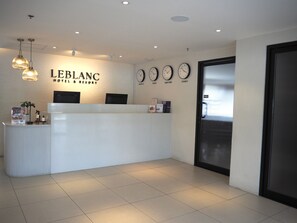 A reception desk with a sign reading 'LEBLANC HOTEL & RESORT' and clocks displaying times for Manila, Tokyo, New York, and Sydney. - LeBlanc Hotel and Resort (Antipolo)