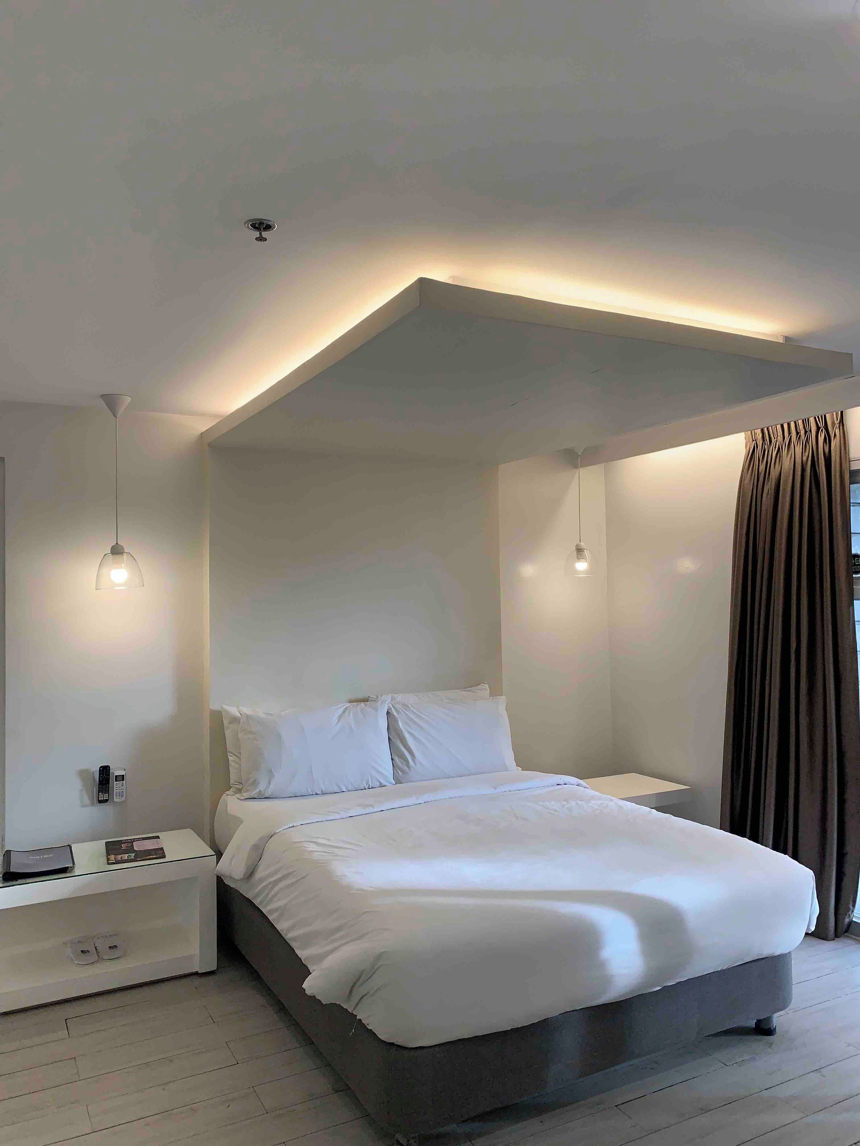 Un dormitorio moderno con una cama grande, mesitas de noche e iluminación colgante.