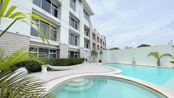 Una piscina al aire libre, sombrillas, sillones reclinables de piscina