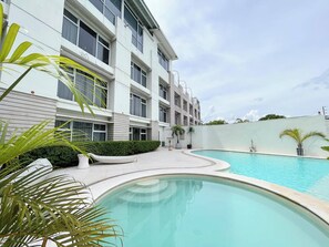 Een buitenzwembad, parasols bij het zwembad en ligstoelen