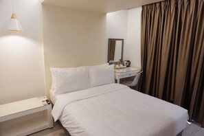 A hotel room with a bed, bedside table, desk, chair, and a mirror.