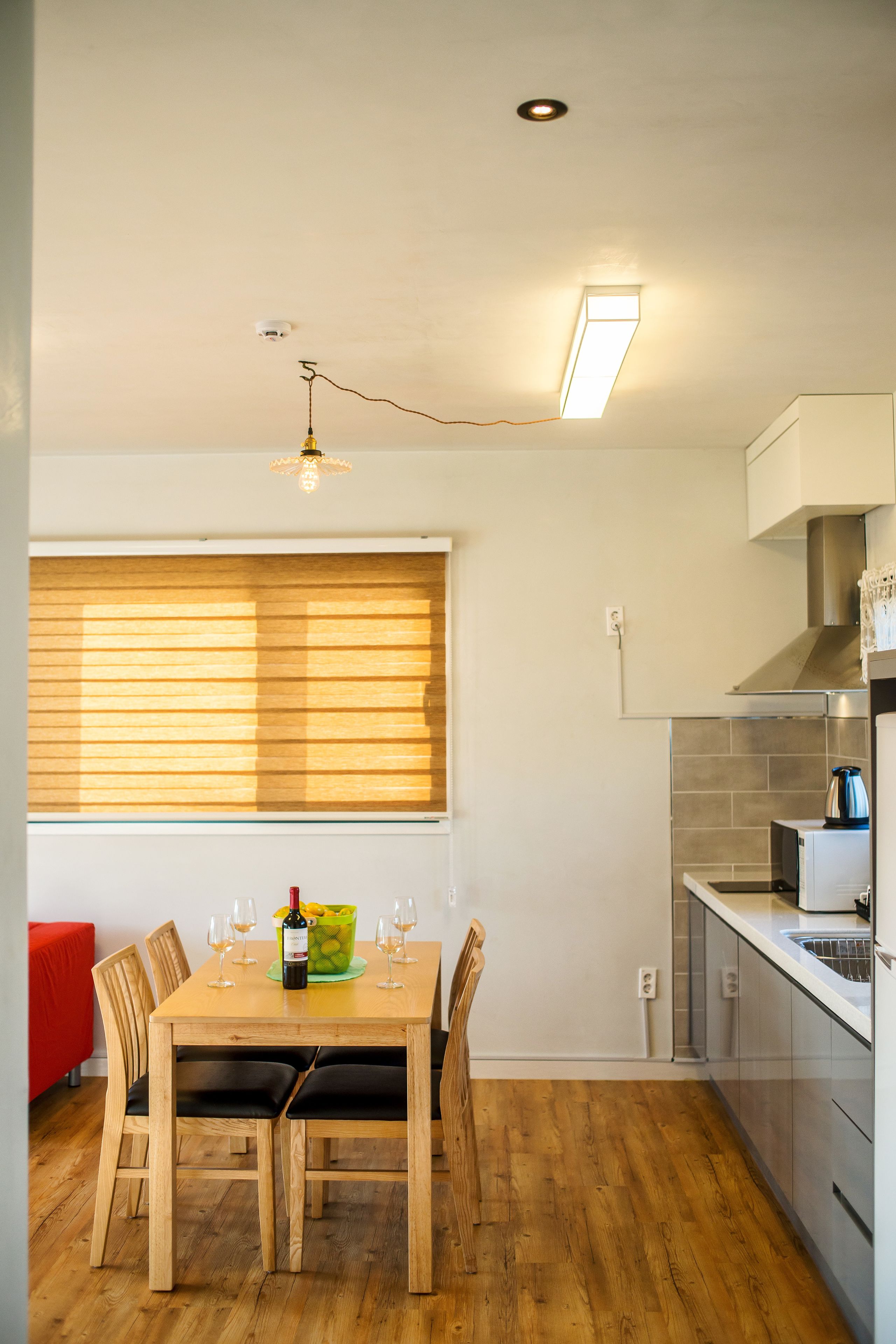 Una cucina moderna con tavolo da pranzo per quattro persone, una finestra con persiane e un lampadario.