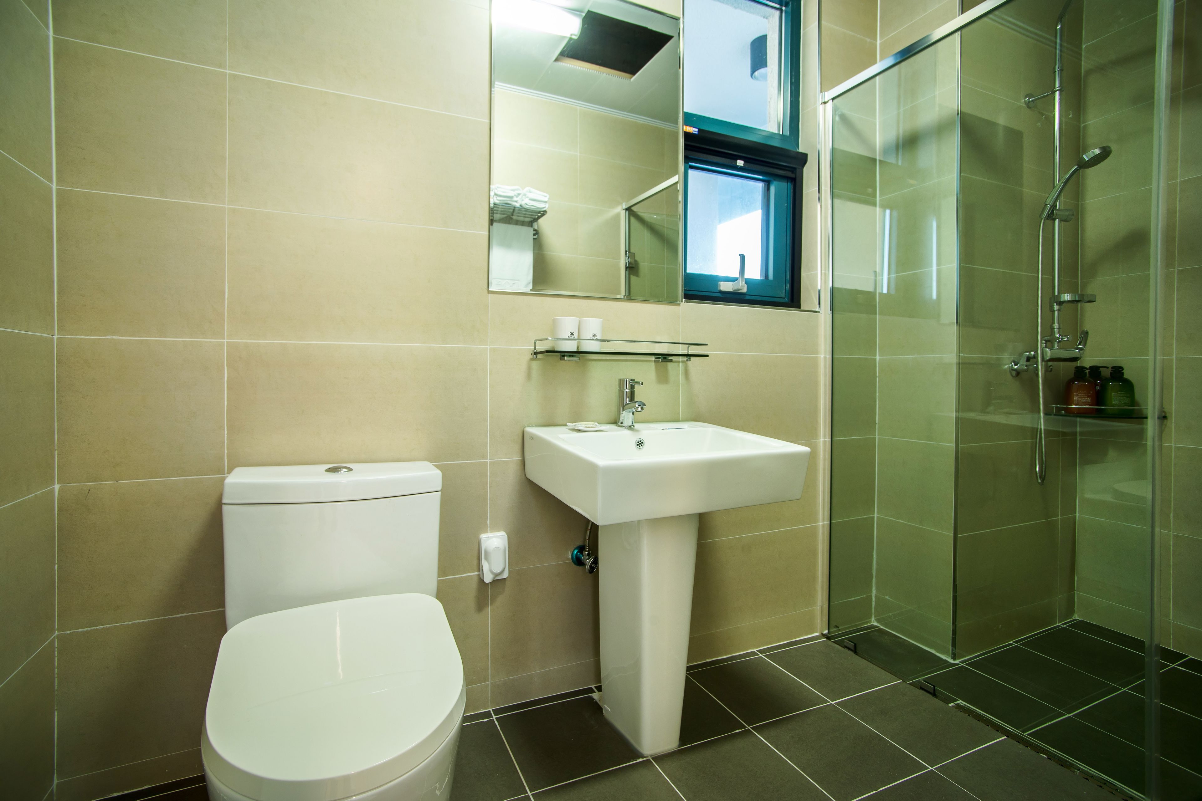 Un baño con inodoro, lavamanos y cabina de ducha de vidrio.