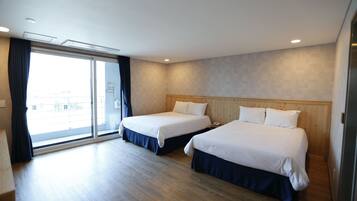 A hotel room with two beds, a sliding glass door to the balcony, and a wooden floor.