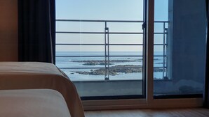 Un dormitorio con un amplio ventanal que ofrece vistas al mar y afloramientos rocosos.