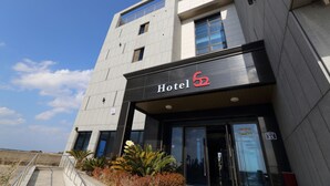 Un hotel moderno con una entrada destacada, amplias ventanas y cielo despejado.