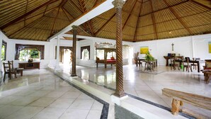 A spacious hall with a high thatched roof, polished tiled floors, and wooden furniture. - Bali Hidden Paradise Villa (Seminyak)