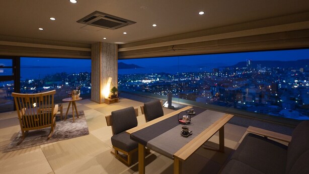 Una sala de estar moderna con vistas panorámicas a la ciudad al anochecer.