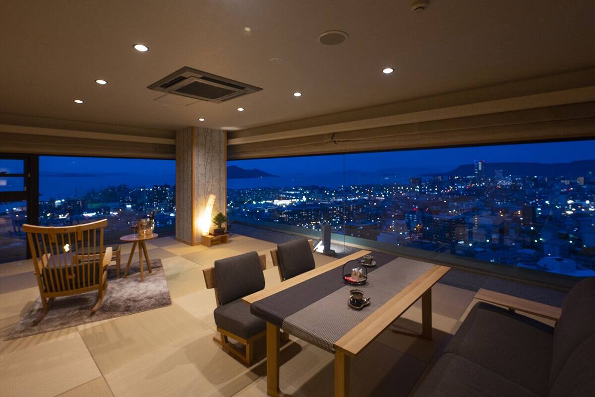 Una sala de estar moderna con vistas panorámicas a la ciudad al anochecer.