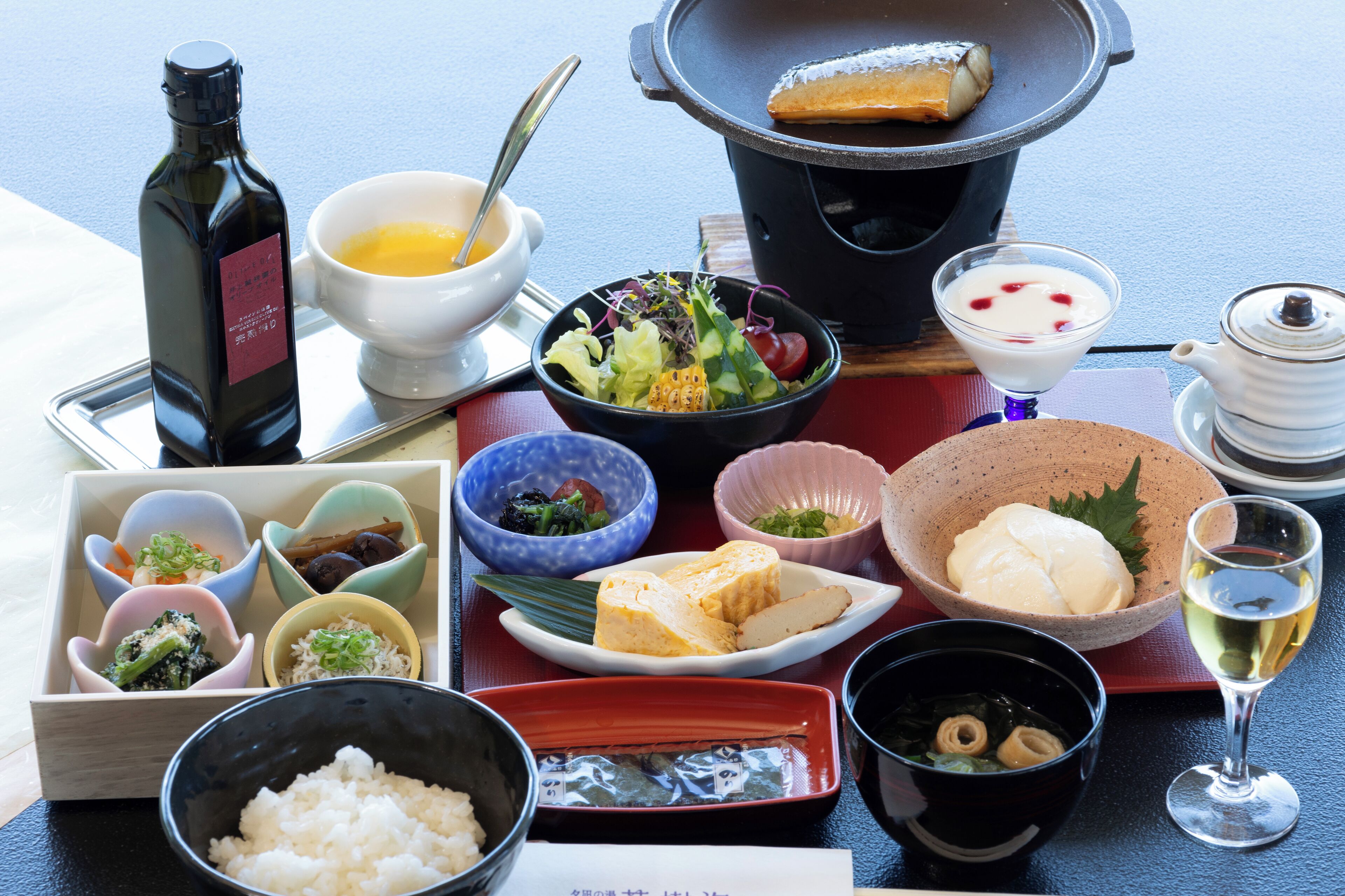 Diverse Japanse gerechten, waaronder sushi, rijst en een pan met eten op een tafel.