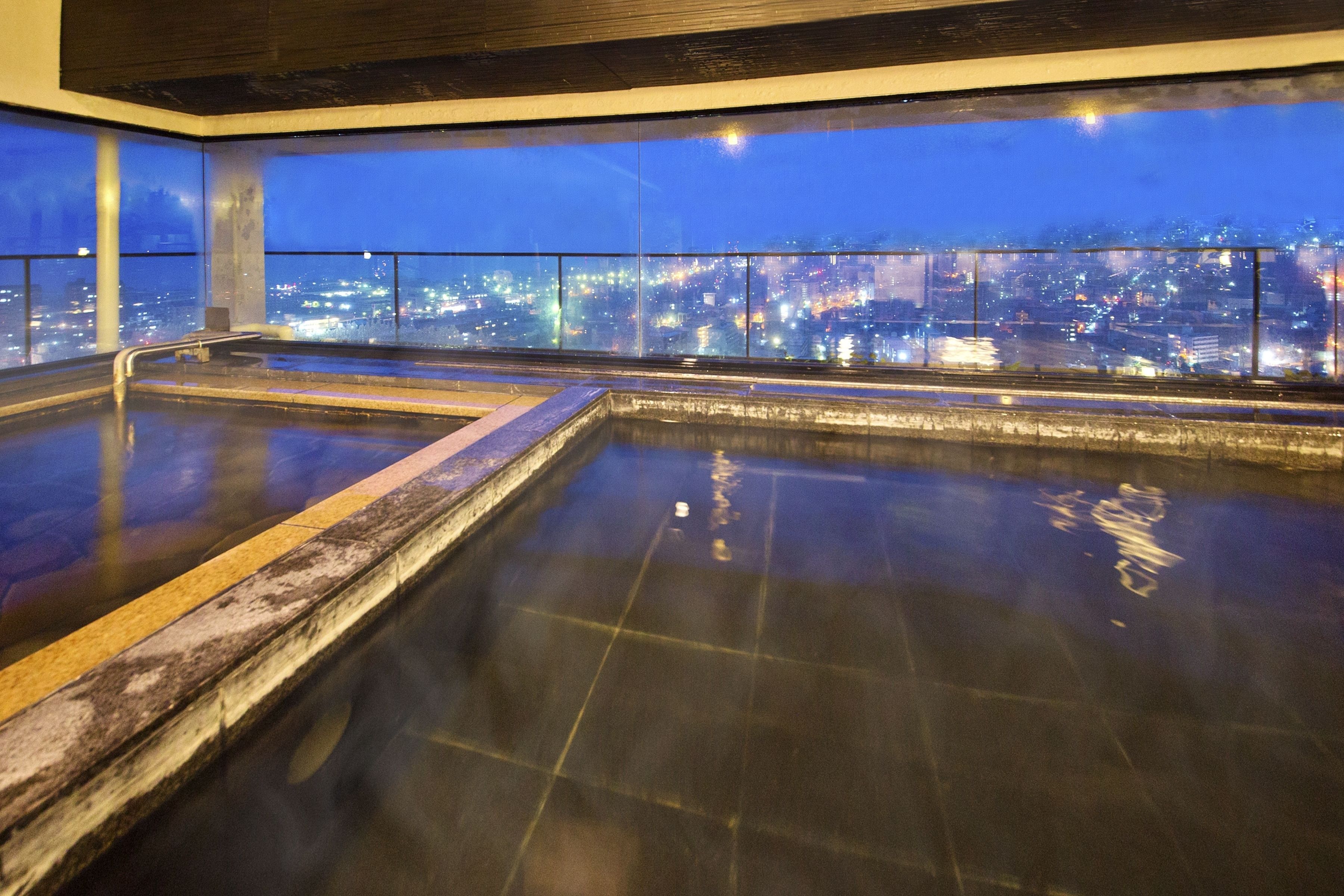 A rooftop pool with a city view at dusk.