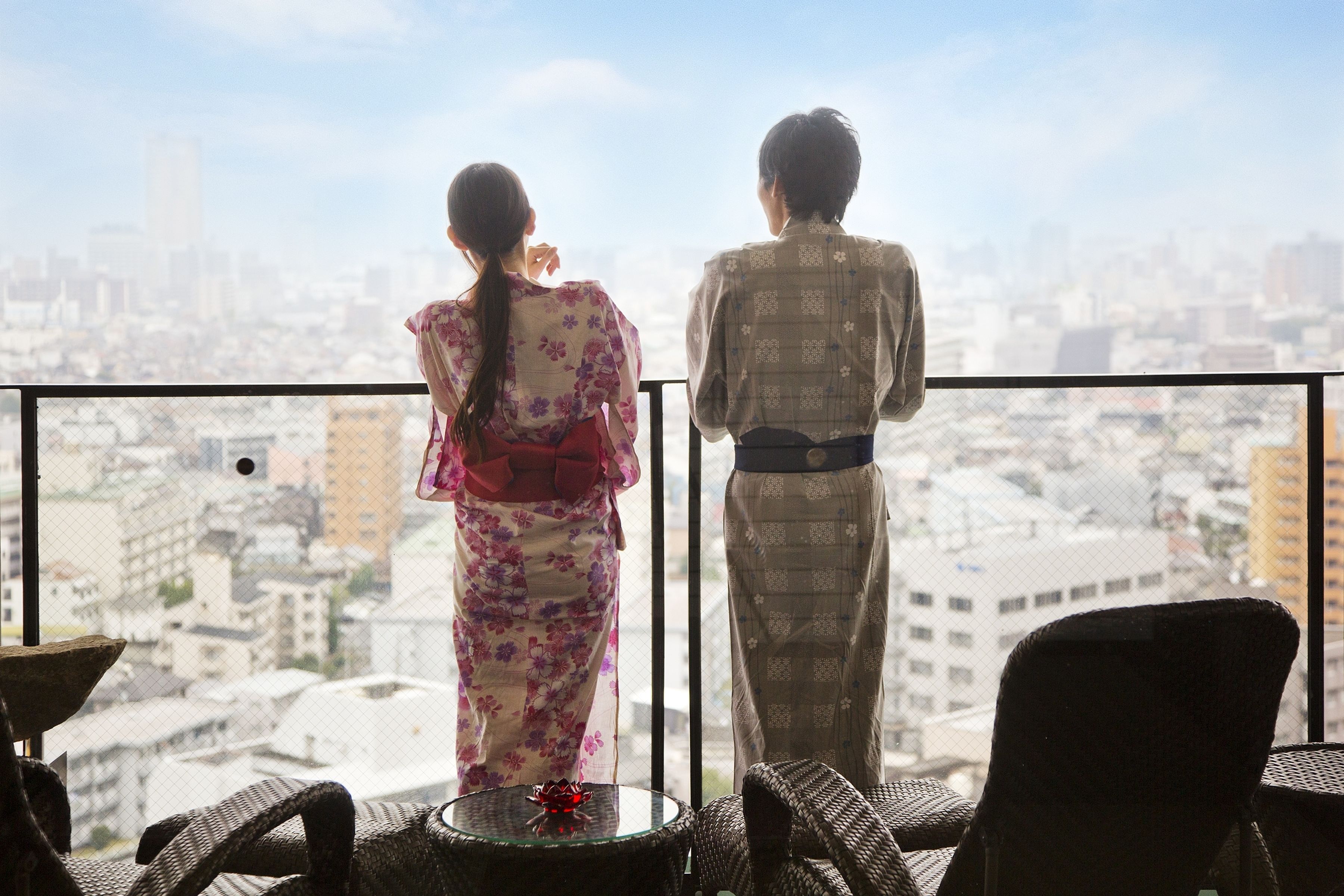 Una pareja parada en un balcón con vistas a la ciudad.