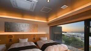 Un dormitorio moderno con dos camas, un ventanal con vistas a la ciudad y un ventilador de techo.