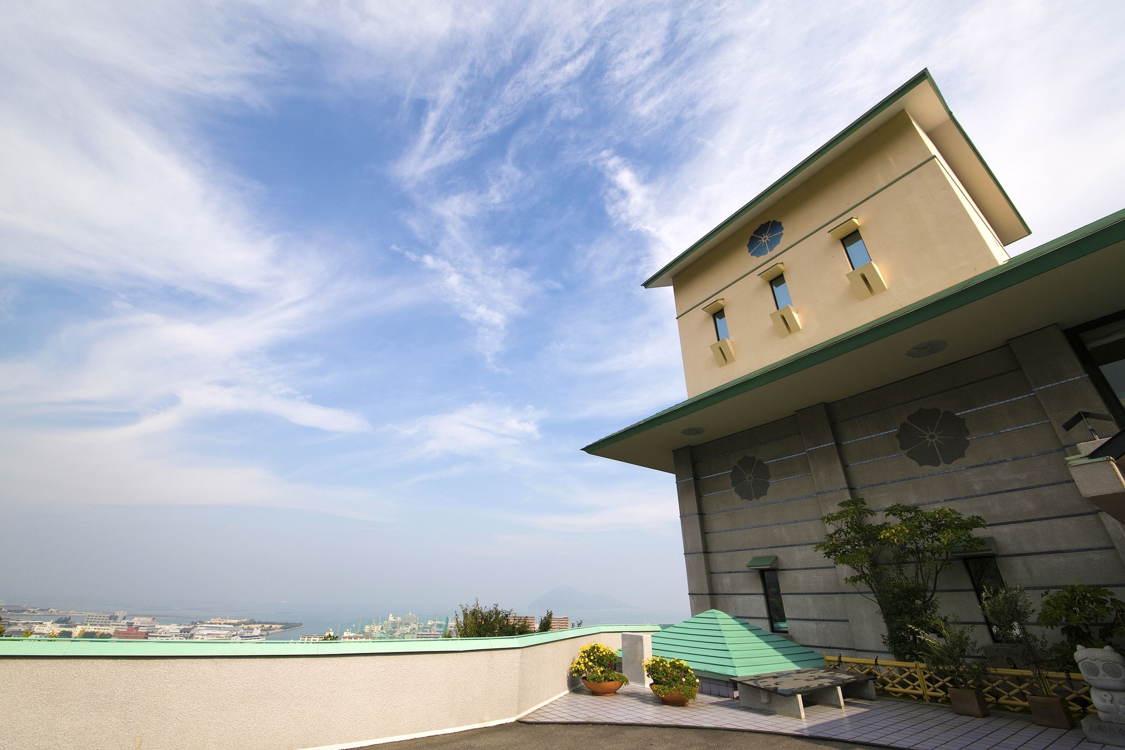 Un bâtiment doté d’un toit plat, d’un auvent vert et offrant une vue sur le paysage urbain en arrière-plan.