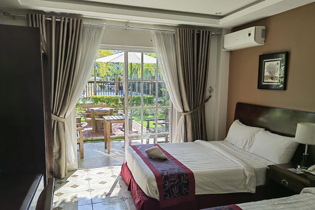 A hotel room with a bed, bedside table, and a view of an outdoor patio with a table and chairs.
