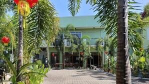A wooden deck with a view of a building with multiple windows and a green facade. - Marand Family Resort (Bauang)