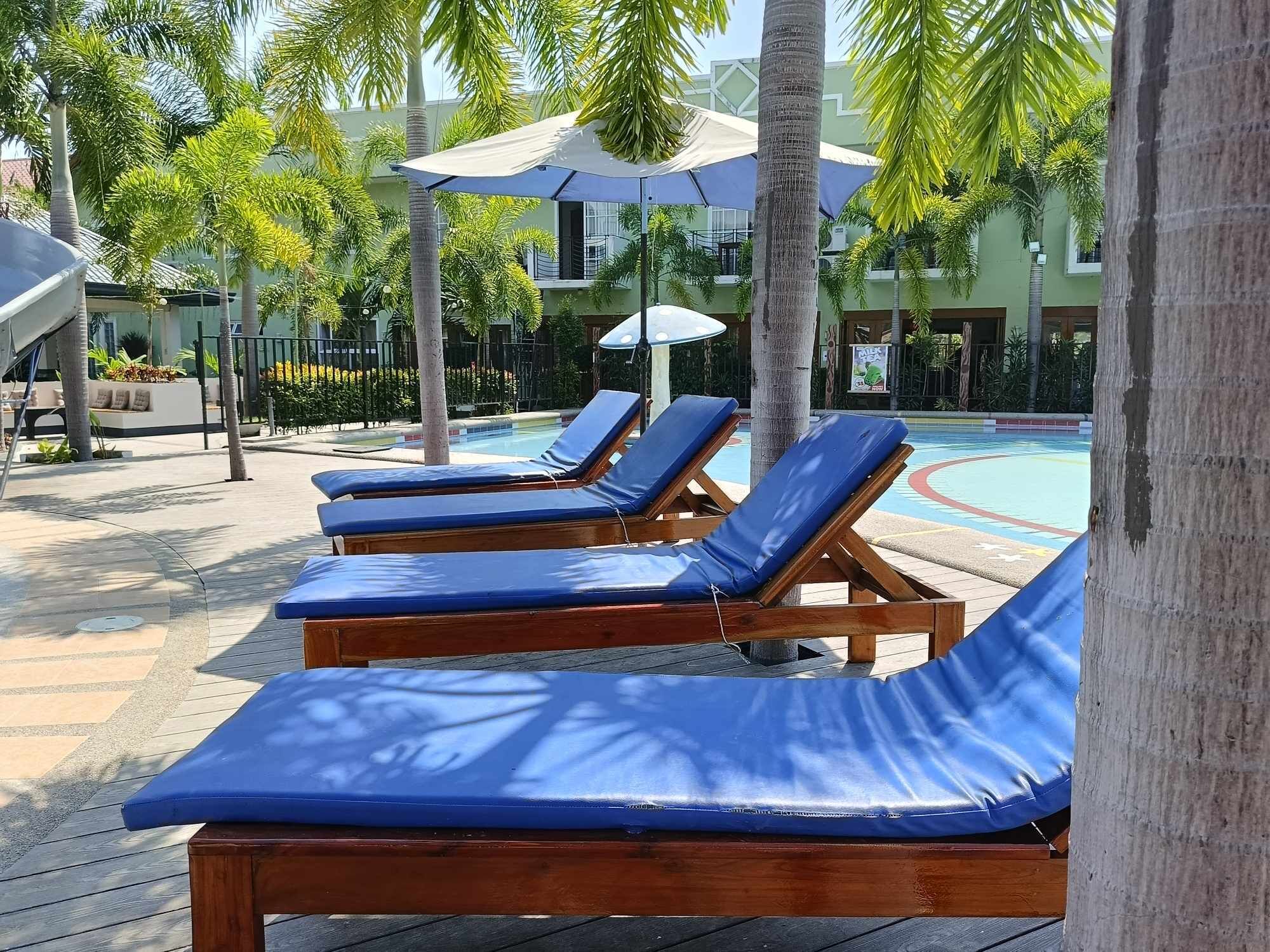 A poolside area with wooden lounge chairs and umbrellas.