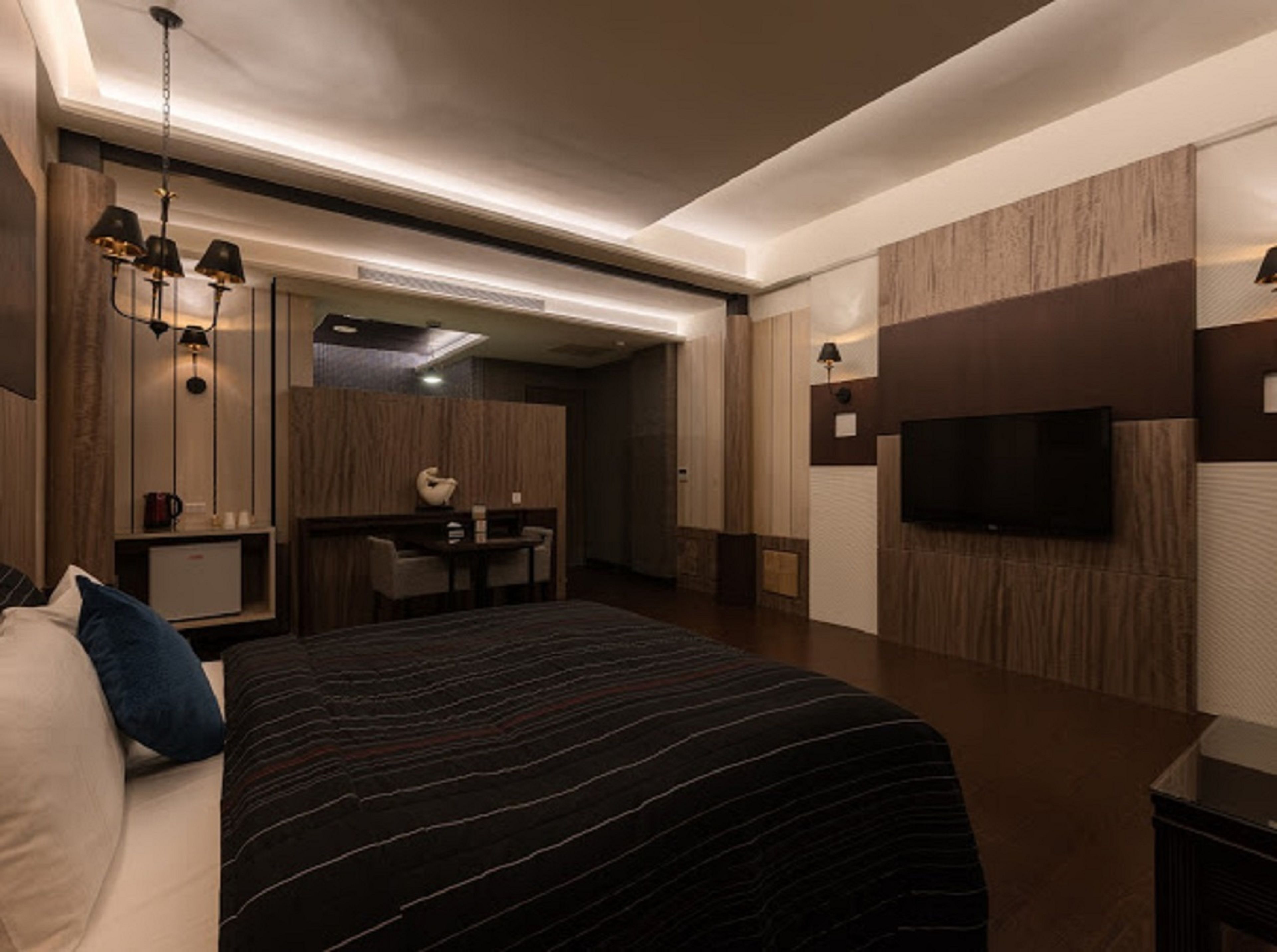 A modern hotel room with a large bed, a desk, and a flat-screen TV mounted on the wall.