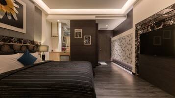 A modern bedroom with a large bed, a nightstand, a mirror, and a dark wooden wall with a floral pattern.