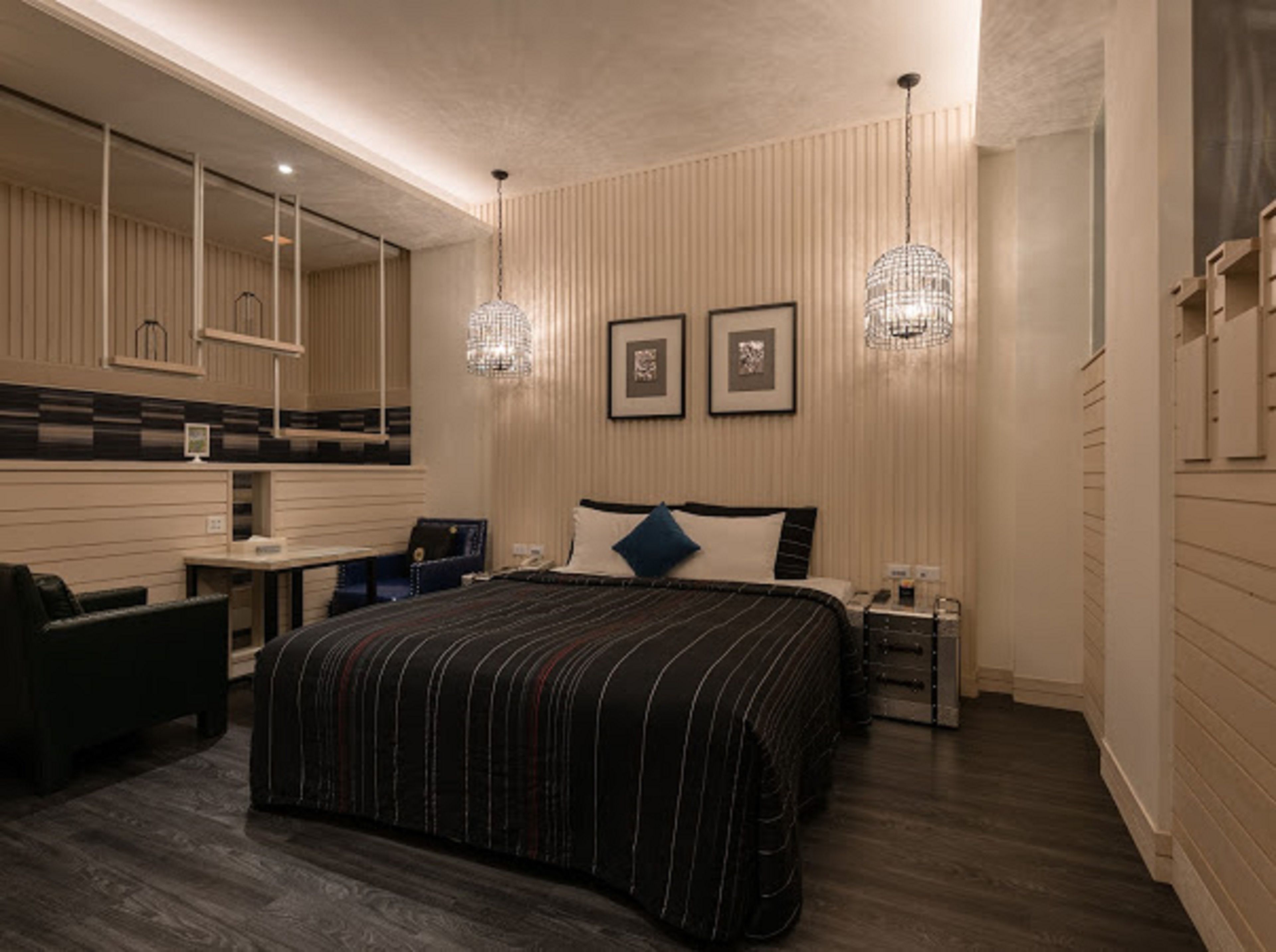 Habitación de hotel moderna con una cama grande, un escritorio y una silla. Hay dos luces empotradas en la pared y cuadros enmarcados sobre la cama.