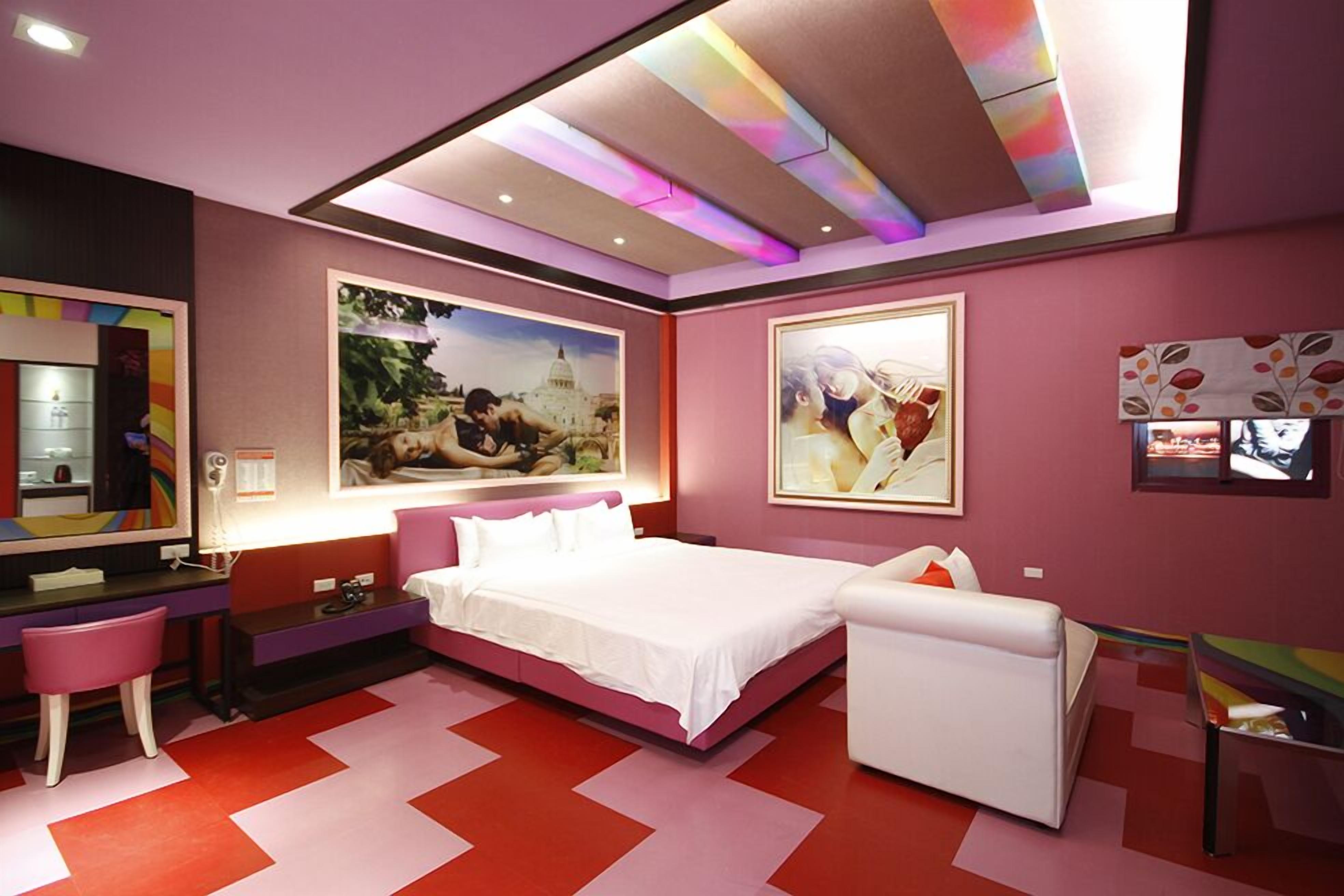 Un dormitorio moderno con una cama grande, un escritorio y una silla. Hay dos cuadros en la pared.