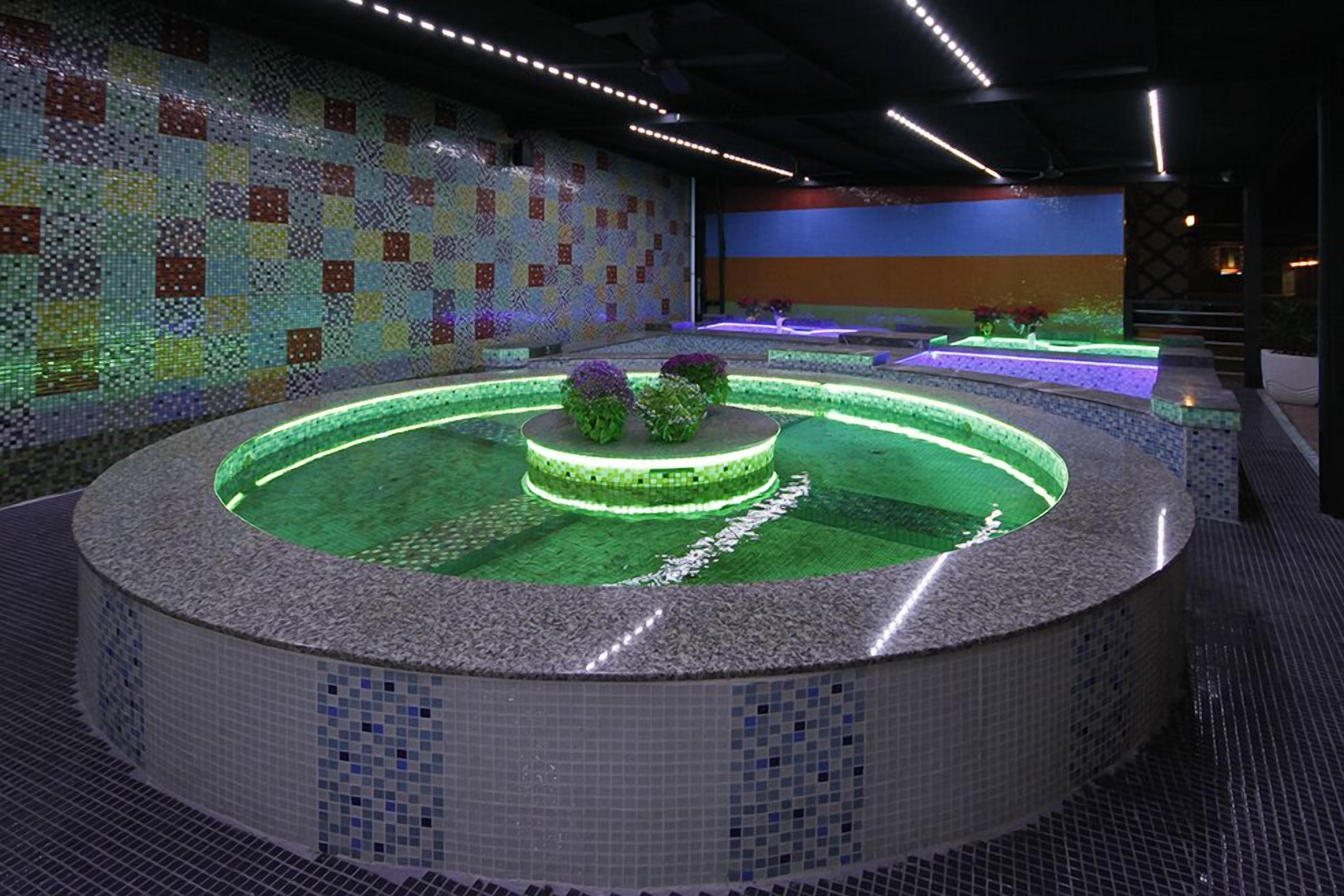 A circular hot tub area with mosaic tile walls and a central island.