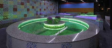 A circular hot tub area with mosaic tile walls and a central island.