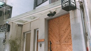 Un edificio con una puerta de madera grande, una ventana pequeña y una planta en maceta.