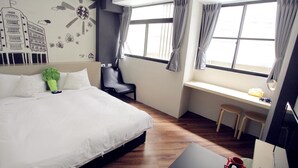 Una habitación de hotel con cama, escritorio y ventana con cortinas.